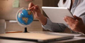 unrecognizable-businesswoman-using-digital-tablet-while-examining-globe-planning-her-vacation