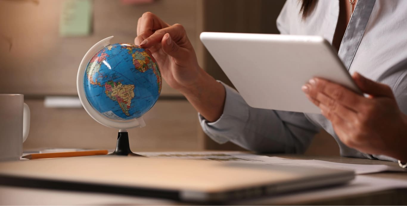unrecognizable-businesswoman-using-digital-tablet-while-examining-globe-planning-her-vacation
